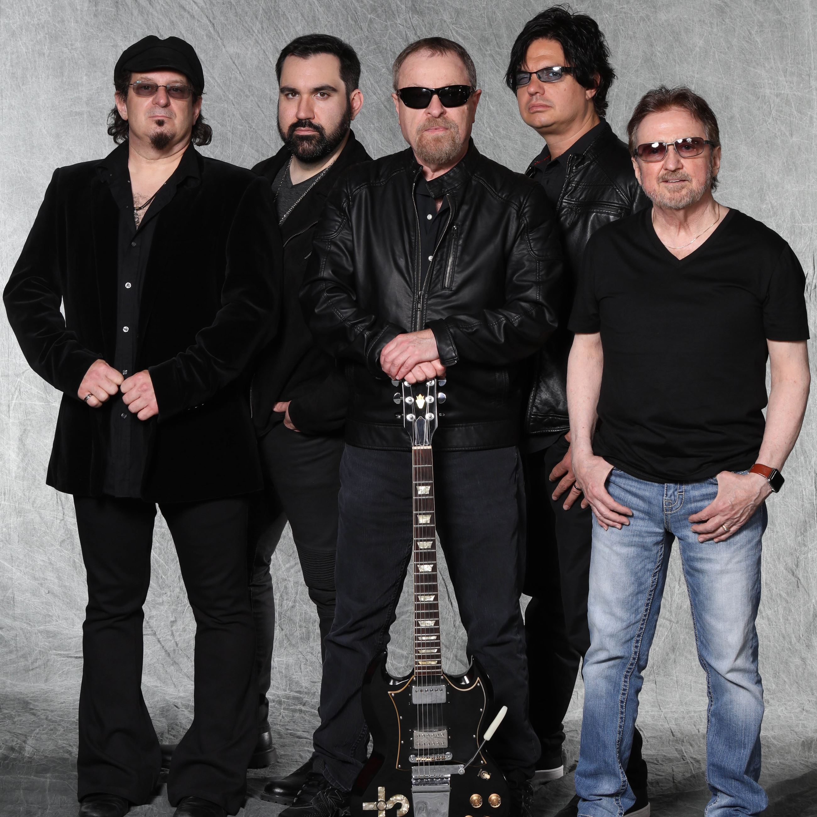 Members of Blue Oyster Cult band stand together with guitar
